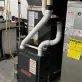 A gray Goodman furnace and a silver HVAC unit with an EnergyGuide label showing 96.1 efficiency in a basement.